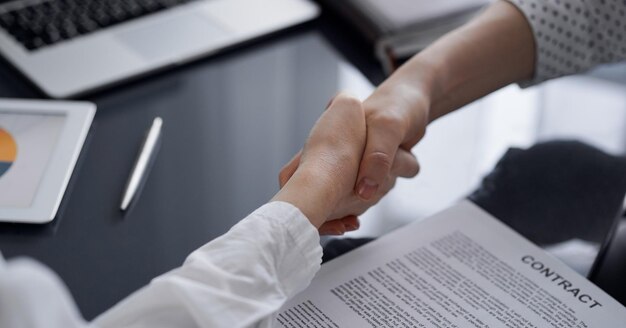 Business people signing contract papers while sitting at the glass table in office, closeup. Partners or lawyers working together at meeting. Teamwork, partnership, success concept.