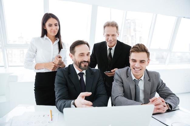 Business people sitting by the table with laptop in office