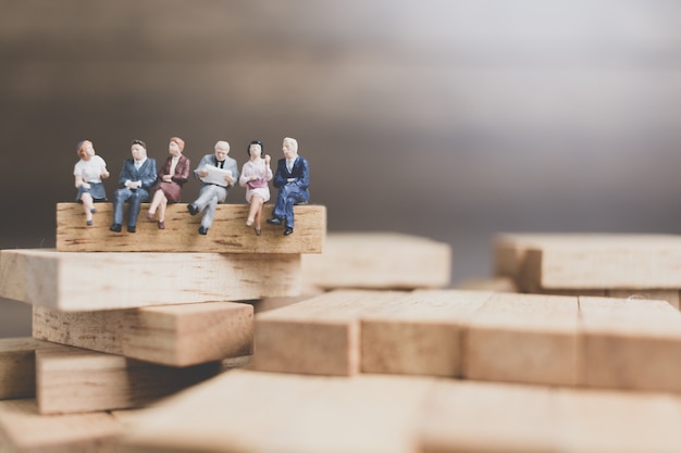 Business People sitting on wood block with wooden background