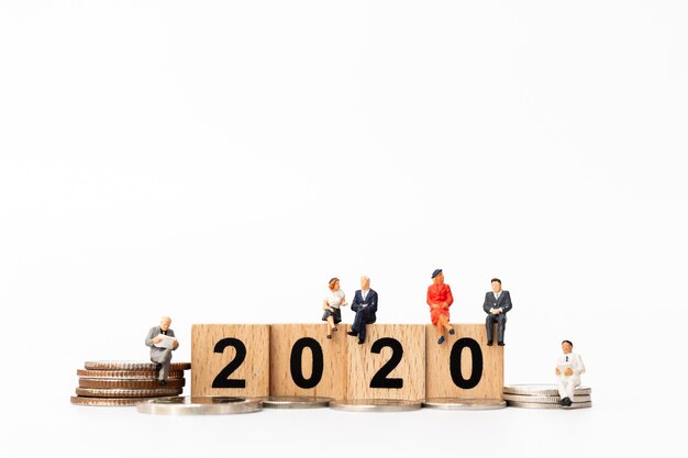 Business people sitting on wooden block number 2020 