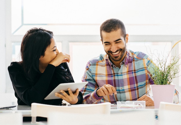business people smiling while using digital tablet in office