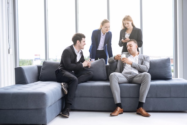 Business people at sofa against window