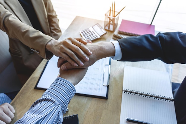 Photo business people stacking hands over papers on table