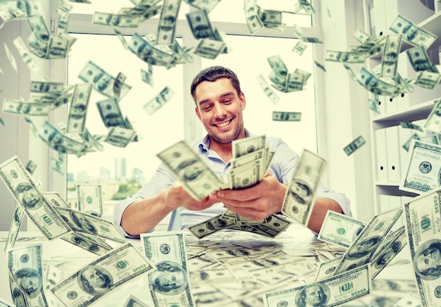 Business, people, success and fortune concept - happy businessman with heap of dollar money at office