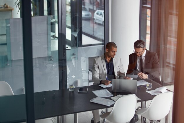 Foto uomini d'affari che parlano e pianificano online per la strategia aziendale o la partnership con il lavoro di squadra uomini insieme in una discussione di riunione con documenti documenti e laptop al tavolo di gestione