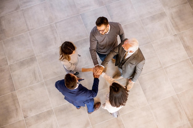 Business people team stack hands as unity gesture in the office hallway