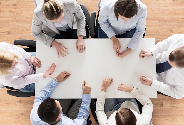 business, people and team work concept - close up of creative team sitting at table in office