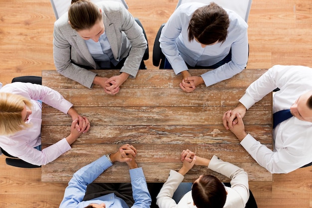 business, people and team work concept - close up of creative team sitting at table in office