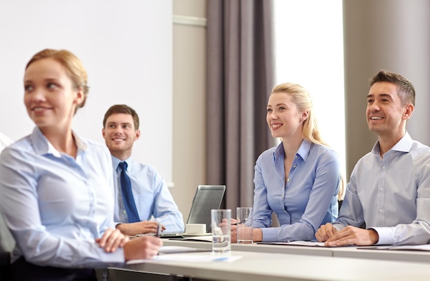 business, people and teamwork concept - group of smiling businesspeople meeting on presentation in office