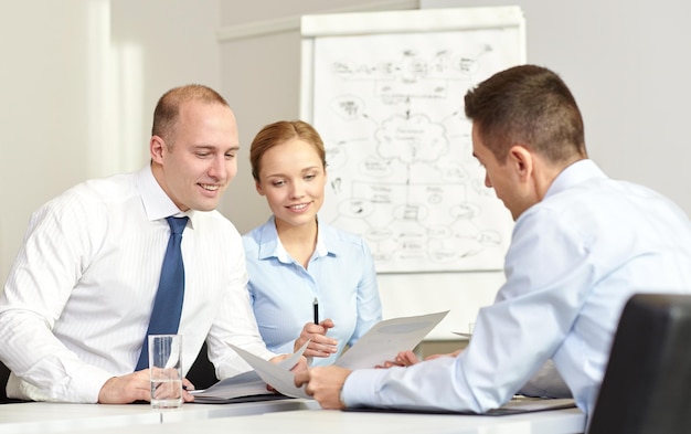 business, people and teamwork concept - smiling business team with papers meeting in office