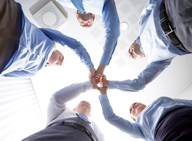 business, people and teamwork concept - smiling group of businesspeople standing in circle and making high five gesture