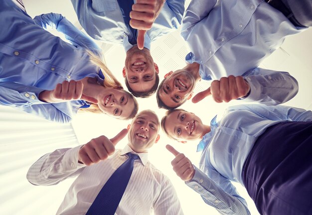 Foto concetto di affari, persone e lavoro di squadra - gruppo sorridente di uomini d'affari in piedi in cerchio e che mostrano il pollice in alto gesto