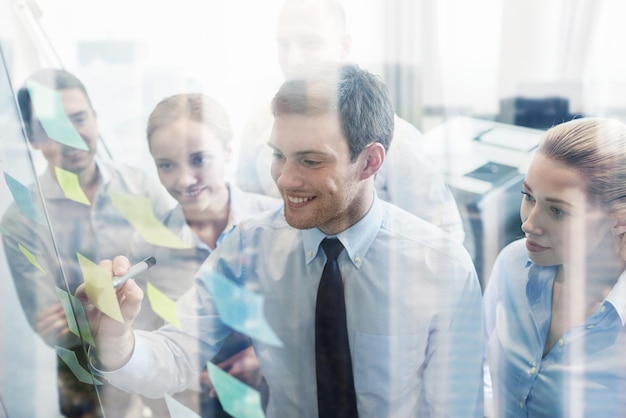 business, people, teamwork and planning concept - smiling business team with marker and stickers working in office