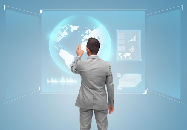концепция бизнеса, людей и технологий - бизнесмен касается виртуального экрана глобусом сзади на синем фоне