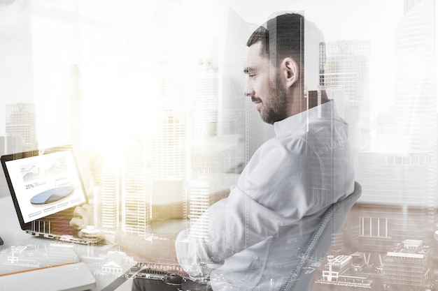 ビジネスマンとテクノロジーのコンセプト ダブルエクスポージャー効果でオフィスの画面にチャートを表示するラップトップコンピュータで作業するビジネスマン