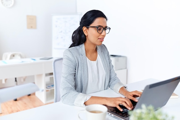 концепция бизнеса, людей и технологий - деловая женщина с портативным компьютером, работающая в офисе