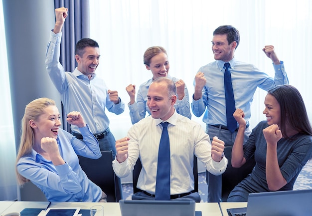 ビジネス、人、テクノロジー、ジェスチャー、チームワークの概念-手を挙げてオフィスでの勝利を祝う笑顔のビジネスチーム