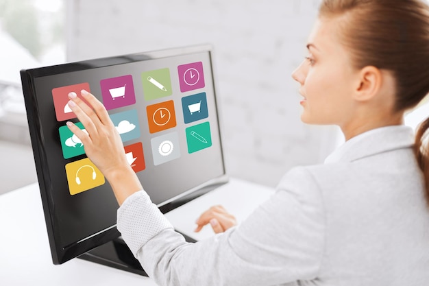 business, people, technology and media concept - woman with application icons on computer touchscreen in office