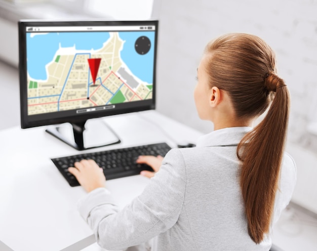 business, people, technology, navigation and education concept - businesswoman or student girl with gps navigator map on screen on computer screen sitting at office table