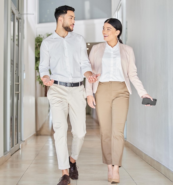 Business people walking and happy conversation in corridor with gossip smile and chat in office Work friends and woman with man for discussion talking or news of project ideas or communication