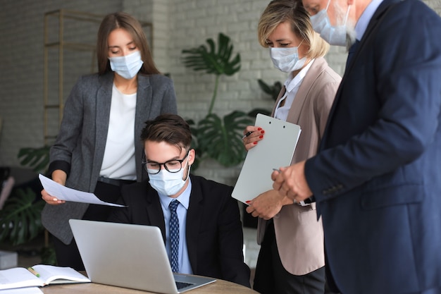 Uomini d'affari che indossano maschere protettive mentre tengono una presentazione in una riunione durante l'epidemia di coronavirus.