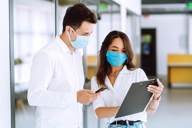 オフィスで働くフェイスマスクを持ったビジネスマン疫病の蔓延を防ぐというコンセプト