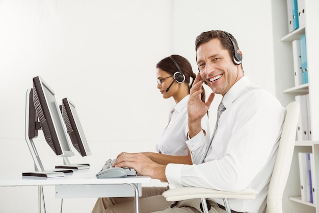 Business people with headsets using computers in office