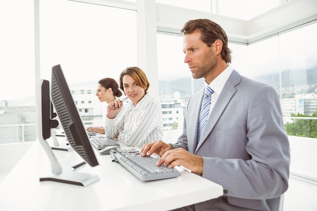 Деловые люди с гарнитурами, использующими компьютеры в офисе