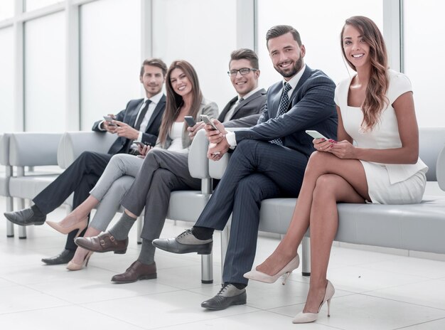 Business people with mobile phones sitting in the bright\
hall