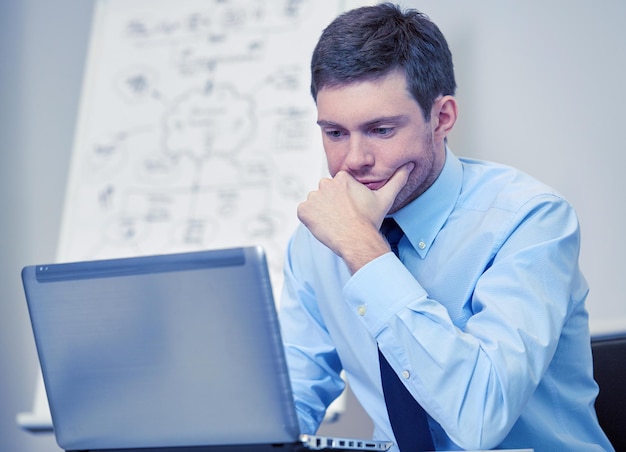 비즈니스, 사람, 작업 개념 - 사무실에서 노트북 컴퓨터와 함께 화이트보드 앞에 앉아 있는 사업가