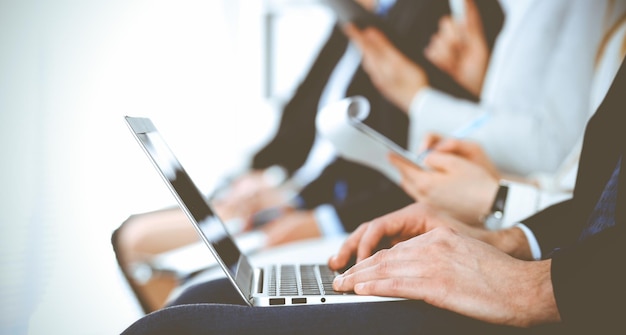 Business people working at meeting or conference, close-up of hands. Group of unknown businessmen and women in modern white office. Teamwork or coaching concept.