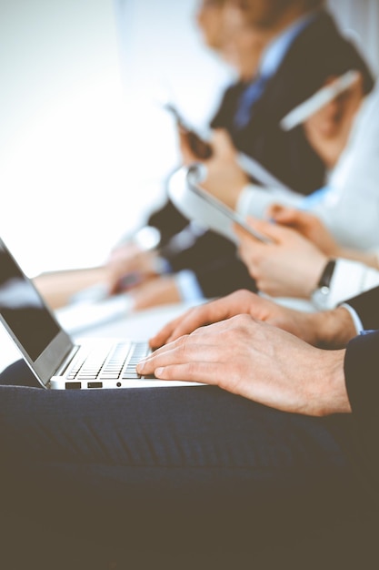 Business people working at meeting or conference, close-up of hands. Group of unknown businessmen and women in modern white office. Teamwork or coaching concept.