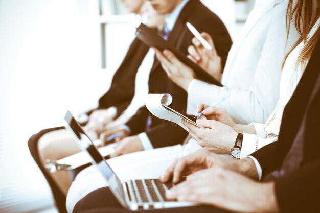 회의나 회의에서 일하는 사업가들, 손을 클로즈업합니다. 현대 흰색 사무실에서 알 수 없는 기업인과 여성 그룹. 팀워크 또는 코칭 개념입니다.