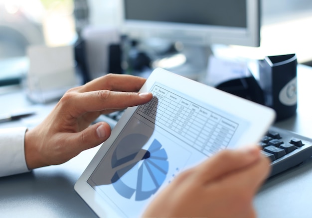 Business person analyzing financial statistics displayed on the tablet screen