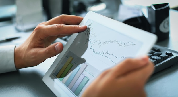 Business person analyzing financial statistics displayed on the tablet screen