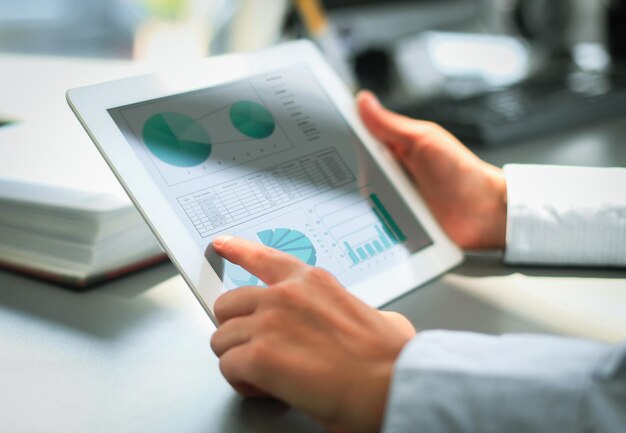 Photo business person analyzing financial statistics displayed on the tablet screen