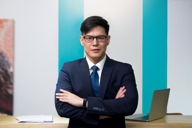 A business person car rental operator or lodging wearing blue suit and glasses is standing with arms crossed 