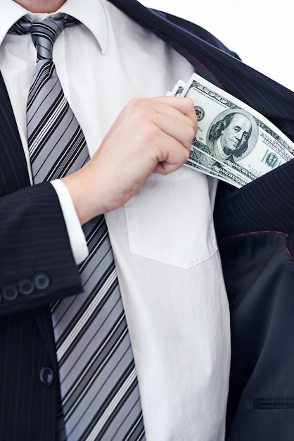 Business person hands and money bribe in pocket for fraud scam or secret on a white studio background Closeup of employee with cash dollar bills or finance in bribery deal or financial exchange