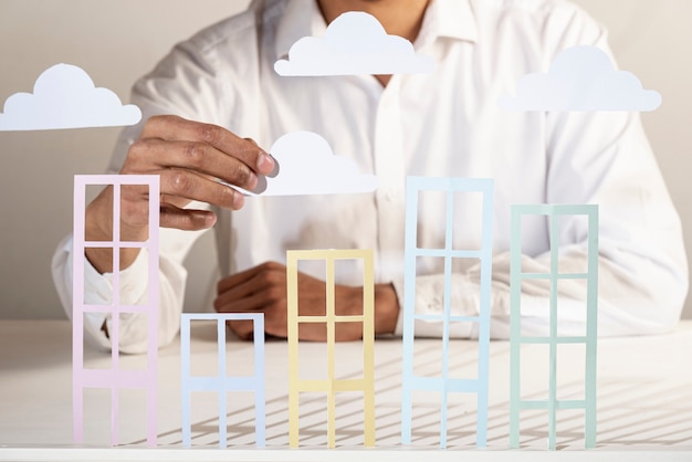 Photo business person and paper buildings and clouds