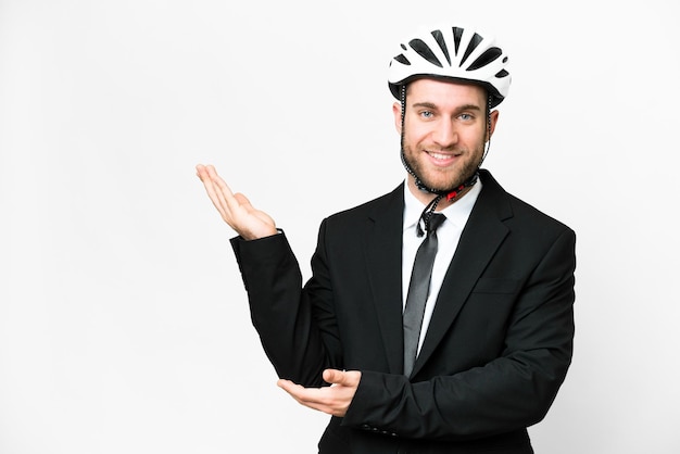 Business person with a bike helmet over isolated white background extending hands to the side for inviting to come