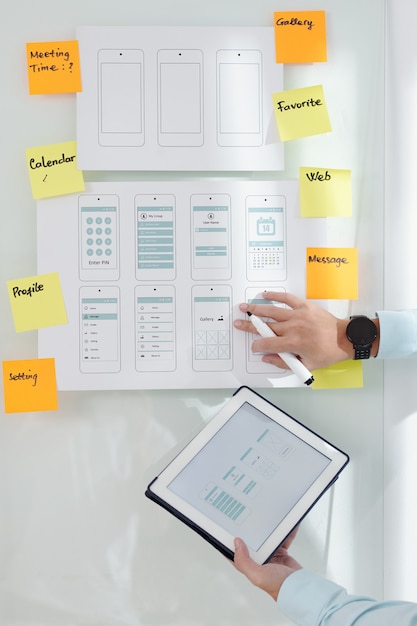 Business person with digital tablet checking mokeup of mobile interface on office wall