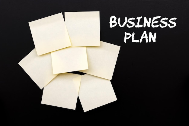 Business Plan text on black board with yellow stocky notes
