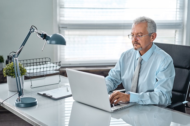 Business portrait of an elderly man. An aged man working on a laptop. Work on removal, freelance.