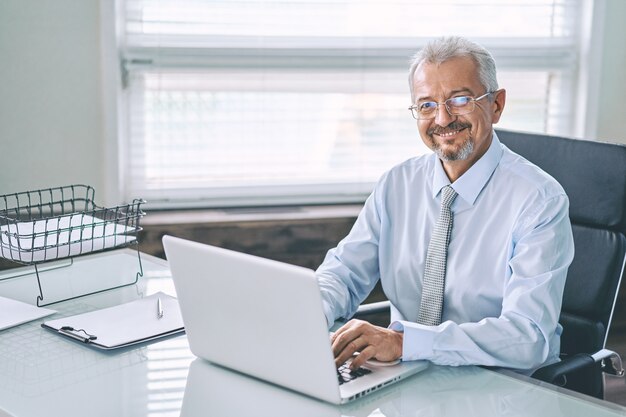 Business portrait of an elderly man working on a laptop