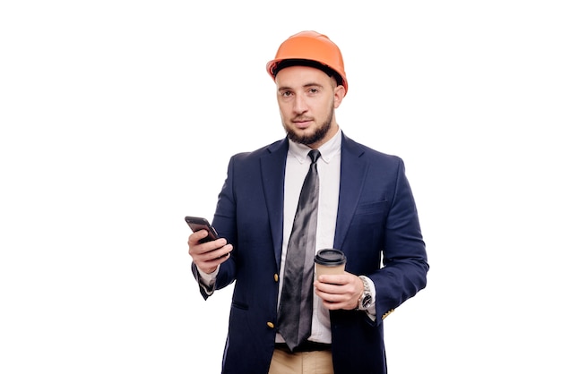 Foto ritratto di affari di imprenditore e sviluppatore sorpreso, parlando di telefono. uomo d'affari in cappello duro con una tazza di caffè in piedi su sfondo bianco. notizie e concetto di freno del caffè