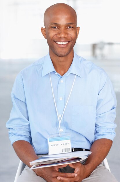 Photo business portrait and young black businessman sitting in workshop and conference room at work convention tradeshow and happy african male corporate worker with documents on lap in presentation