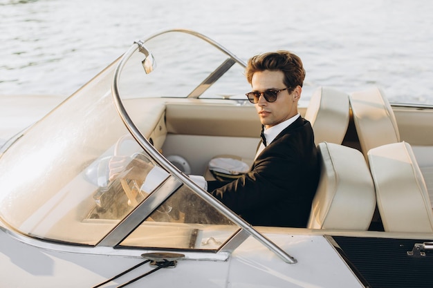 Business portrait of young man in suit and sunglasses posing on
a yacht