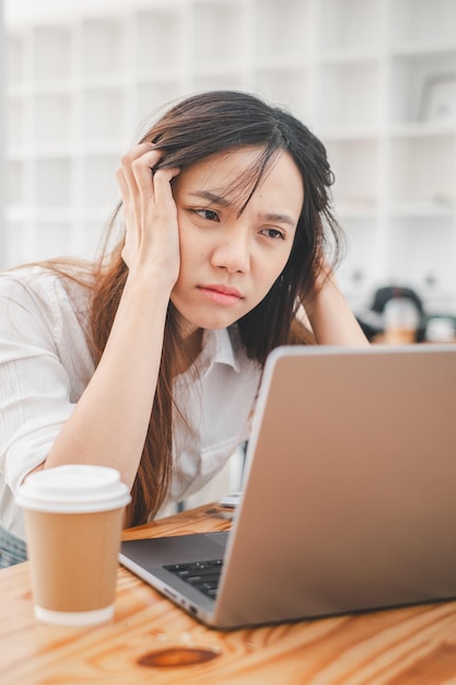 business problem solving concept a stressed young woman appears anxious as she concentrates on her laptop possibly dealing with a tight deadline or challenging work in a bright office space