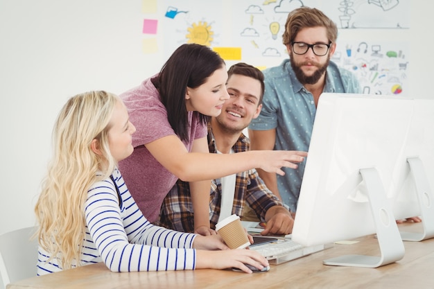 Business professionals discussing at computer desk 