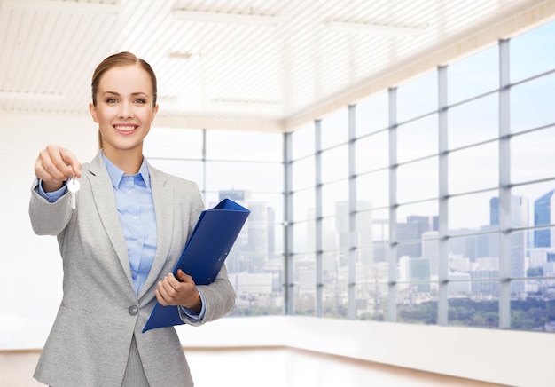 business, real estate, banking and people concept - smiling businesswoman with folder and keys over office room or new apartment background